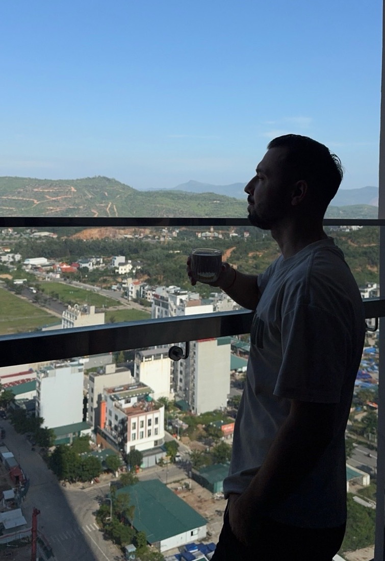 Дмитрий с чашкой на балконе 21 этажа, вид на горы и город
